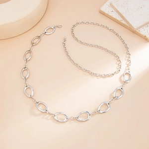 Close-up of a silver geometric hollow round waist chain with lobster clasp on a stone surface