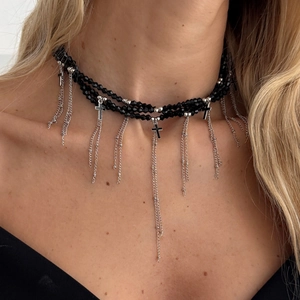 Nahaufnahme eines schwarzen Perlen-Chokers mit silbernen Quastenketten und Kreuzanhänger