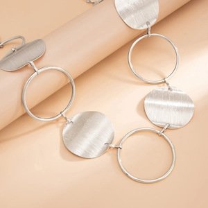 Silver metal waist chain with brushed circular plates and rings on a minimalist column