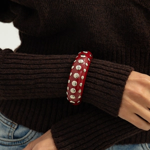 Macro shot of red resin wide cuff bracelet featuring silver stud accents on a model