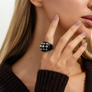 Close-up of a punk style black resin ring with silver stud detailing worn on the finger