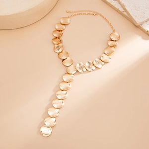 Close-up of golden Y-shaped tassel necklace featuring brushed metal discs and long chain drop