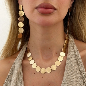 Detail of brushed gold geometric leaf necklace and matching earrings set on a model
