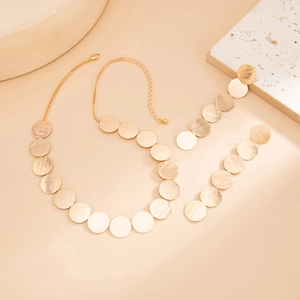 Detail of gold geometric round discs with brushed metal finish on necklace and bracelet