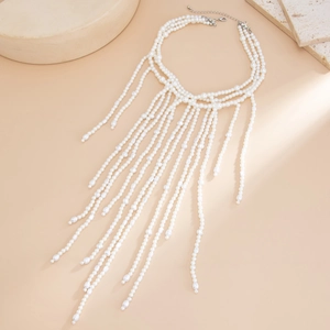 Elegante meerlaagse parelchoker ketting met lange franje kwastjes op steen decor