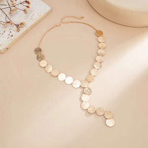 Macro shot of gold Y-shaped necklace with brushed metal disks and lobster clasp