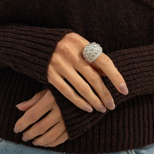 Close-up of resin ring with silver metal studs on hand with knit sweater background