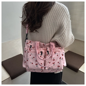 Close-up of pink cherry print tote bag with functional zipper pockets worn by a model