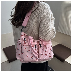 Detail view of pink canvas tote bag featuring red cherry prints and multi-zipper pockets