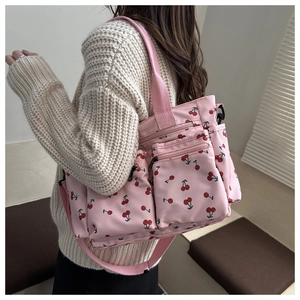 Borsa tote rosa con stampa di ciliegie e multitasche indossata da una modella in interni
