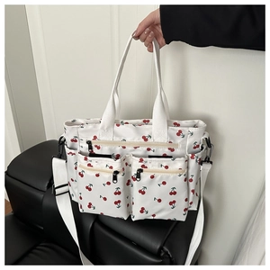 Detail view of large tote bag featuring red cherry prints and multiple functional zipper pockets