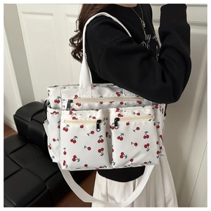 Detail view of large cherry print tote bag featuring multiple functional zipper pockets