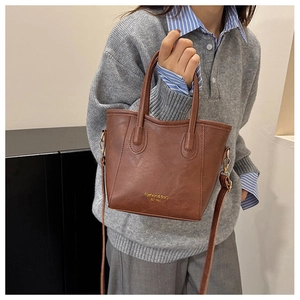 Détail du sac seau marron avec gravure dorée et mousquetons métalliques de la bandoulière