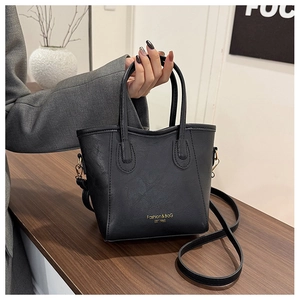 Détail d'un sac seau noir en cuir avec lettrage doré et doubles poignées robustes