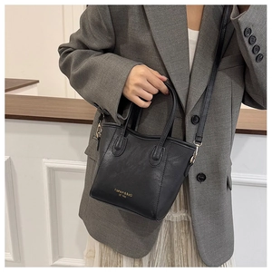 Detail showing high-capacity black leather crossbody bag with adjustable strap and handles