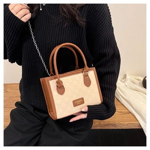 Détail montrant la texture à carreaux et le logo doré sur le sac bandoulière