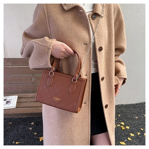 Détail du sac cabas gaufré marron foncé avec bandoulière chaîne et plaque métallique