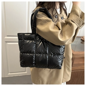 Détail d'un sac cabas noir matelassé porté par un mannequin dans un décor d'intérieur