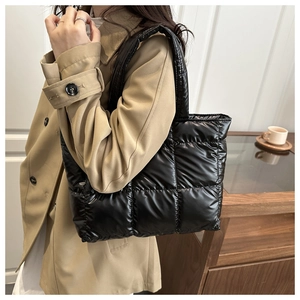 Sac fourre-tout noir brillant matelassé porté épaule dans une ambiance café d'automne