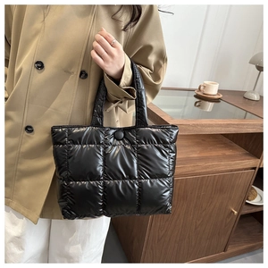 Gros plan d'un sac cabas matelassé noir montrant la texture en nylon brillant et les coutures