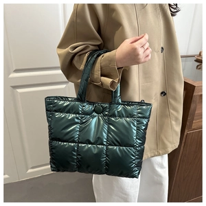 Détail d'un sac cabas matelassé vert foncé avec finition métallique et bouton pression