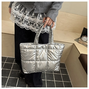 Gros plan d'un sac cabas argenté matelassé avec texture rembourrée et fermoir rond