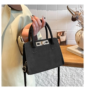 Detail of the black matte suede handbag featuring a silver twist lock and round handles