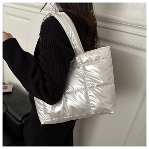 Détail latéral du sac cabas matelassé argenté avec bandoulière large et coutures carrées