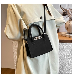 Detail of black matte leather handbag with silver rotary buckle and slender strap