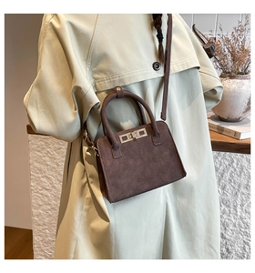Detail of a dark brown suede crossbody bag styled with vintage aesthetic and art props