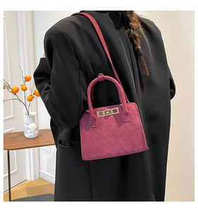Detail of plum suede crossbody bag with metal buckle and shoulder strap on black coat
