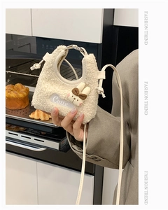 Nahaufnahme der cremefarbenen Plüschtasche mit Cutie-Stickerei und Hasen-Anhänger