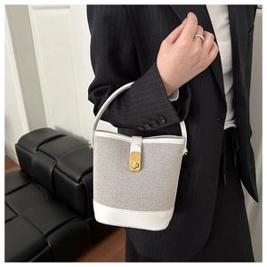 Detail of white mesh bucket bag with leather trim and golden metal clasp closure
