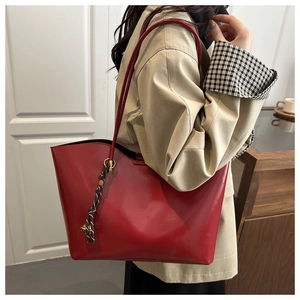 Detail of red oil wax leather tote bag with gold hardware and plaid silk scarf decoration