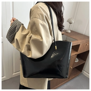 Detail showing the large capacity black tote bag's glossy finish and slim shoulder straps
