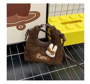Detail der braunen Plüschtasche mit 'Cutie' Stickerei und 3D-Hasen-Accessoire