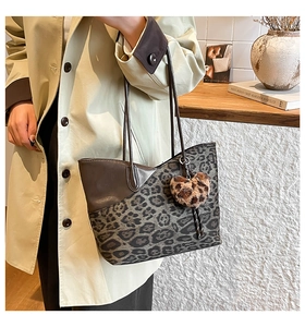 Detailansicht der Leopard-Print Shopper-Tasche mit braunem Lederbesatz und Herz-Anhänger am Model