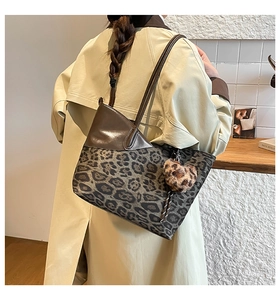 Detail of leopard print patchwork tote bag with a heart charm shown on a shoulder