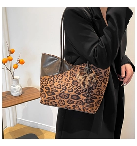 Detailed side view of leopard print tote bag with plush heart charm and leather straps