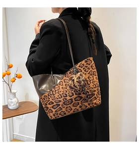 Detail of a large leopard print tote bag with heart charm shown on model's shoulder