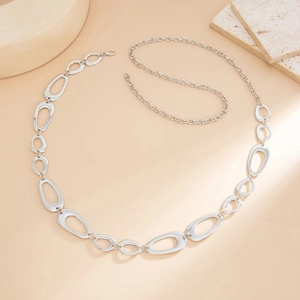 Close-up of geometric hollow oval chain links and lobster clasp on silver metal waist chain