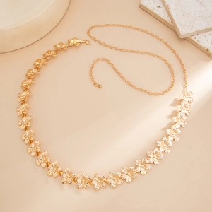 Detail of golden metal waist chain featuring embossed five-petal flower links and adjustable end