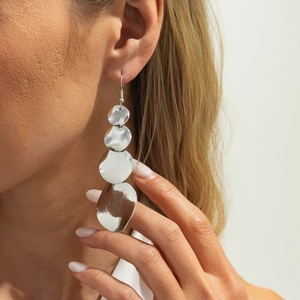 Detail of silver brushed metal tiered floral earrings on model with high gloss finish