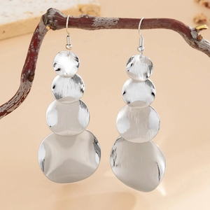 Detail of silver layered earrings with brushed metal texture hanging on a branch