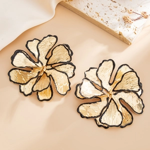 Exaggerated golden leaf earrings with irregular textures and black edges in still life