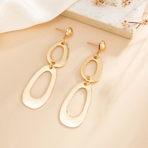 Close-up of golden triple-layered oval dangle earrings on a luxury silk background