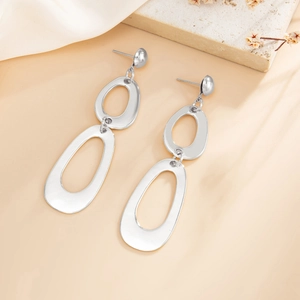 Detailed view of silver geometric cascading oval earrings on a white satin background