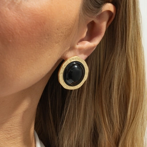 Retro oversized round earrings with hammered gold metal and black resin center on model