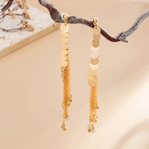 Detail view of golden tassel earrings with round sequins and crystals on a branch