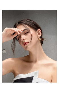 Detail shot of a model wearing gold 18k floral stud earrings with a shiny metallic finish